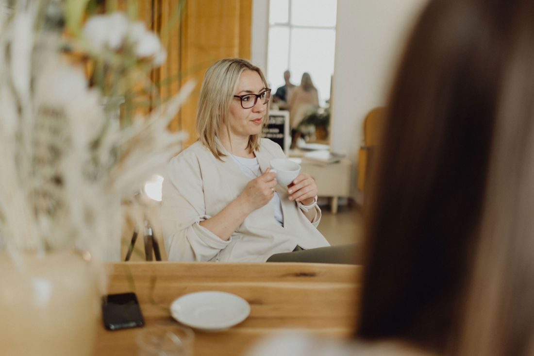 Entspannte Frau mit Brille genießt eine Tasse Kaffee in stilvoller, moderner Umgebung mit gemütlicher Atmosphäre.