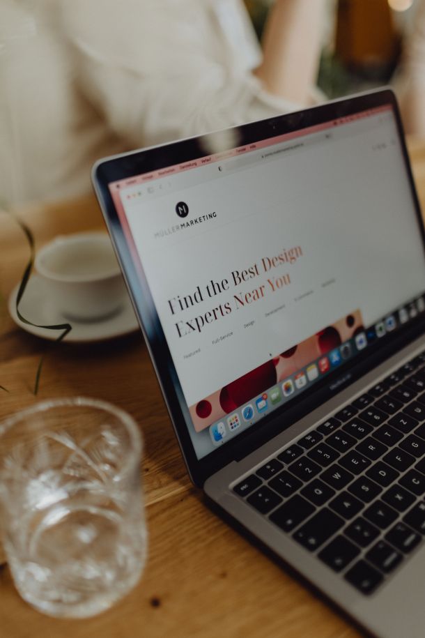 Laptop auf Holztisch mit geöffneter Webseite 'Find the Best Design Experts Near You', modern und professionell gestaltet.